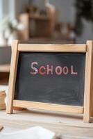 Chalkboard displays the word SCHOOL in white chalk, surrounded by a cozy wooden teachers desk and soft-focus background that evokes a warm, nostalgic educational atmosphere photo