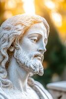 A beautifully sculpted statue of Jesus Christ stands illuminated by soft, warm sunlight filtering through trees. The serene expression radiates a sense of divine peace photo