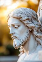 A sculpted statue of Jesus Christ stands bathed in sunlight. Soft focus and a warm glow emphasize his peaceful face. Trees create a blurred background in the outdoor setting photo