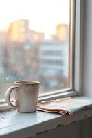 A cracked hostel window offers a hazy view of a city skyline at sunset. Dust coats the sill, while an empty coffee mug and a folded map hint at past adventures and quiet moments spent contemplating photo