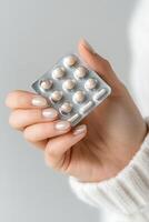 Hands with neatly manicured nails hold a pack of birth control pills. The setting features a blurred medical office backdrop, emphasizing a professional yet inviting atmosphere photo