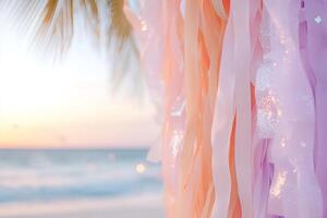 Ombre streamers transition from deep orange to coral pink and lavender, evoking a tropical sunset. Soft palm silhouettes and ocean waves create a serene backdrop filled with golden light photo