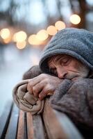 A middle-aged homeless man sleeps on a park bench, using a rolled-up jacket as a pillow. Wrapped in a faded blanket, he appears isolated as distant streetlights glow softly photo