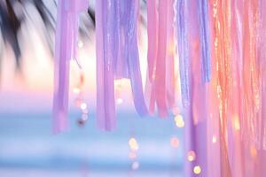Soft ombre streamers transition from deep orange to coral pink and lavender, capturing the essence of a tropical sunset, framed by gentle ocean waves and palm silhouettes photo