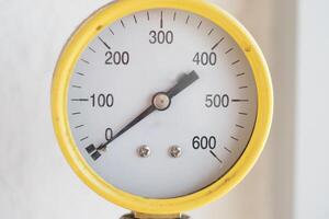 Pressure gauge with yellow casing displaying measurement values photo