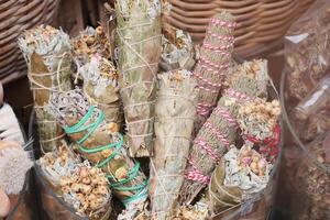 Various bundles of herbs and sage for smudging displayed in a market photo