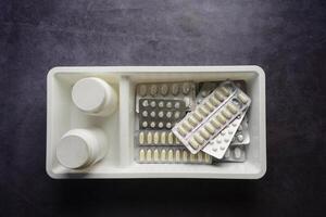 Assorted medication bottles and pill packs on a gray surface photo