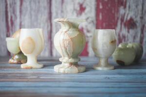 Decorative onyx vases and cups on a rustic wooden table photo