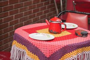 Colorful table setting with a red teapot and decorative cloth photo