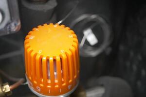 Bright orange dial on mechanical device in workshop setting photo