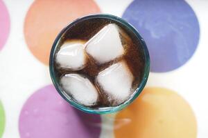 Refreshing drink with ice cubes on a colorful table surface photo