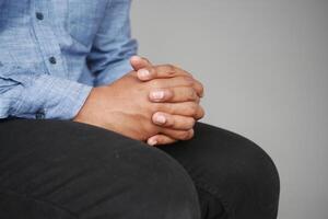 A man sits with hands clasped, deep in thought during a discussion photo