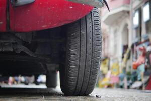 Red car tire in urban setting on a busy street photo
