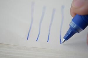 Writing with a blue pen on a blank page in a workspace photo