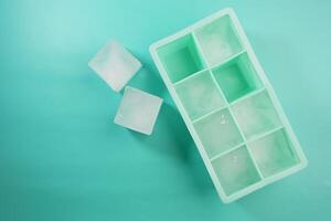 Ice cubes arranged neatly in a green ice tray on a flat surface photo
