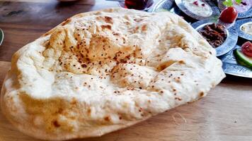 Freshly baked naan bread served with a variety of dishes photo