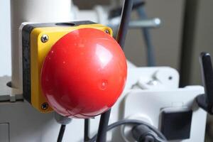 Red emergency stop button on machinery in a workshop setting photo