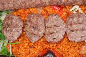 Grilled kebabs served on colorful spiced rice with vegetables photo