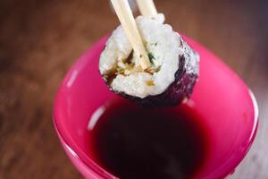 Sushi roll being dipped in soy sauce for a tasty bite photo