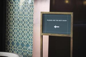 Sign directing visitors to alternative entrance near decorative wall photo