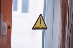 Warning sign reminding to exercise caution near open window photo