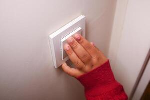 Child reaching to turn on light switch in cozy indoor setting photo