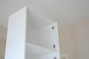 White cabinet with empty shelves in a bright room photo
