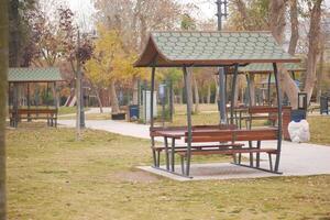 Deserted park with wooden shelters and empty benches in autumn photo