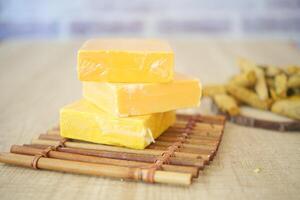 Yellow cheese blocks arranged on a bamboo tray with snacks photo