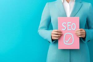 Professional in a patterned suit holding a sign with SEO against a bright blue background. photo