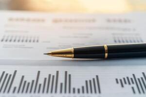 A close-up of a pen resting on financial documents featuring graphs and statistics, symbolizing business analysis and decision-making. photo