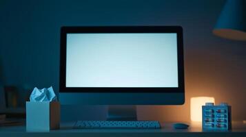 A dimly lit workspace featuring a blank computer screen, a tissue box, and a lamp, creating a calm and focused atmosphere. photo