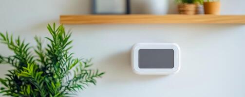 Sustainability of Indoor Air Quality IAQ concept. Smart thermostat mounted on a wall with plants and a wooden shelf in a modern setting. photo