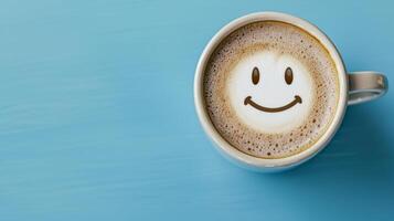 A cozy coffee cup with a smiley face design on the frothy surface, resting on a blue table. photo