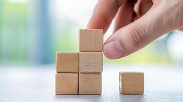 A hand is placing a wooden block on a small tower of blocks, symbolizing construction and creativity. photo