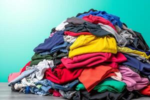 A colorful heap of various clothing items stacked together, set against a gradient teal background. photo