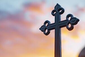 A close-up of an ornate cross silhouetted against a colorful sunset, symbolizing faith and spirituality. photo