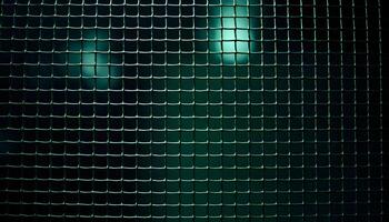Textured metal mesh background under dim ambient light, with a focus on the fine details of the weave and a slight greenish tint photo