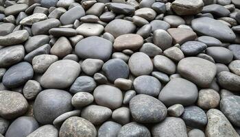 Smooth gray river rocks of various sizes on a surface photo