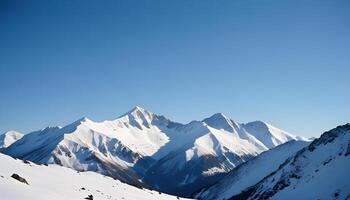 Snow covered mountain peaks under clear blue sky with sharp ridges and shadows photo