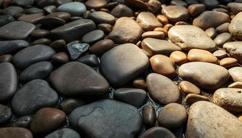 Smooth, rounded river rocks in various shades of brown, gray, and black, arranged in a natural pattern on the ground photo