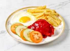 Chicken chop, sunny side up egg Egg, loaded fries, fresh cucumber and tomato slices served in plate isolated on marble background side view of singapore breakfast food photo
