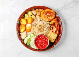 Malaysian Nasi Lemak Feast include coconut rice, sambal, fried anchovies, peanuts, cucumber, and hard boiled egg served in small bowl isolated on marble background side view of singapore food photo