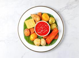 Malaysian Rojak set with Peanut Sauce, fried fritters, sesame seeds, vegetables, and tofu served in plate isolated on marble background top view of singapore food photo