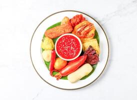 Malaysian Rojak set with Peanut Sauce, fried fritters, vegetables, tofu and banana leaf served in plate isolated on marble background top view of singapore food photo