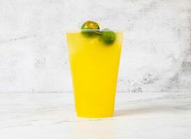Refreshing Calamansi Lime Drink with ice cubes served in plastic cup isolated on marble background side view of Singapore beverage photo