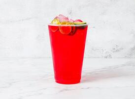 syrup limau or red rose syrup with lime with ice cubes served in plastic cup isolated on marble background side view of Singapore beverage photo