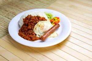 English Breakfast platter include Minced Meat with Rice, Egg, Sausage and mixed vegetables served in plate isolated on table side view of Hong Kong food photo