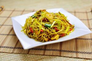 Xingzhou Fried Rice Noodles include vermicelli stir fried with shrimp, vegetables, and curry powder served in plate isolated on table closeup side view of Hong Kong food photo
