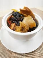 Agaricus Blazei, Fish Maw, Conch Head and Bamboo Chicken Soup served in broth isolated on background closeup top view of Hong Kong food photo